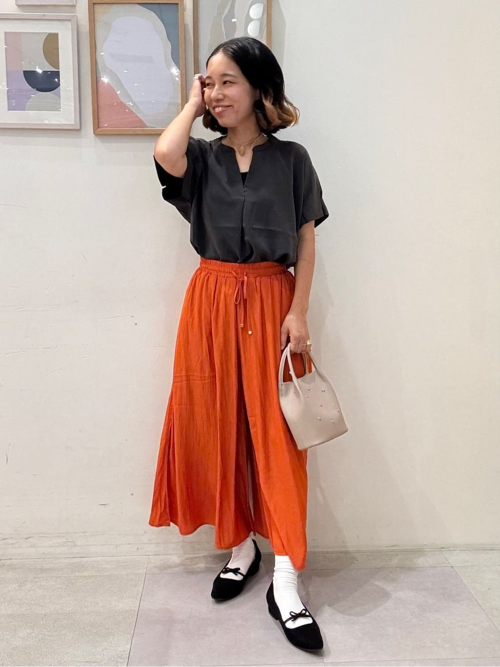 グレー系のシャツ/ブラウス、オレンジ系のその他パンツ、ベージュ系のショルダーバッグを着用したレディースの夏コーディネートの1枚目の写真