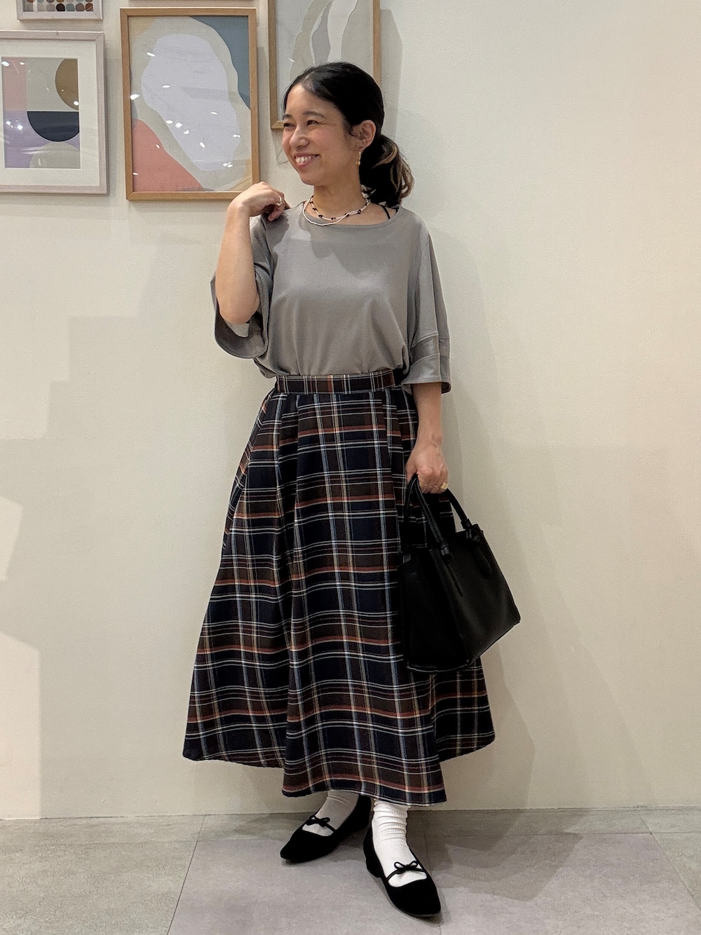 ブラック系のトートバッグ、グレー系のTシャツ/カットソー、ブラウン系のスカートを着用したレディースの春コーディネートの1枚目の写真