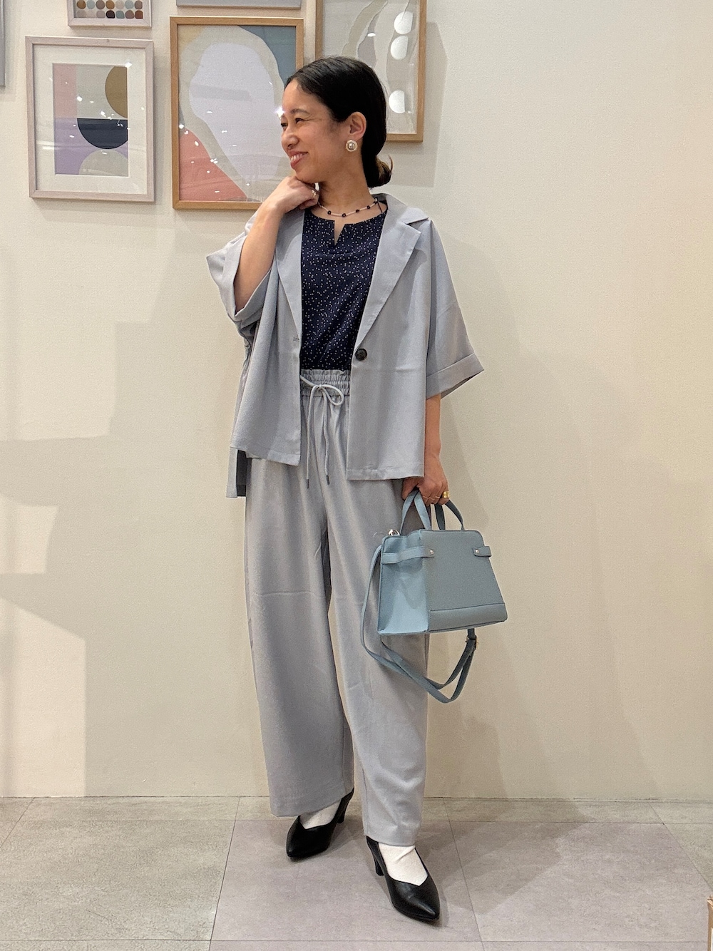 ブラック系のパンプス、ブルー系のシャツ/ブラウス、ブルー系のショルダーバッグを着用したレディースの春コーディネートの1枚目の写真