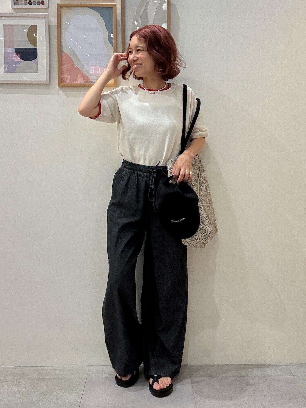 ホワイト系のニット/セーター、ブラック系のデニムパンツ、ベージュ系のトートバッグを着用したレディースの夏コーディネートの1枚目の写真