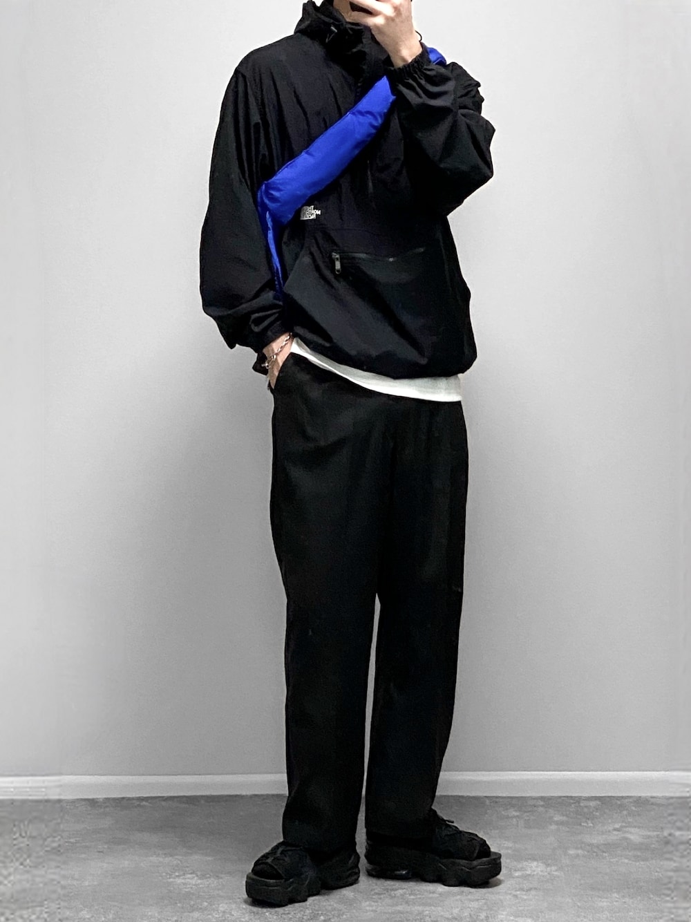 ブラック系のマウンテンパーカー、ホワイト系のタンクトップ、ブラック系のスラックスを着用したメンズの春コーディネートの1枚目の写真