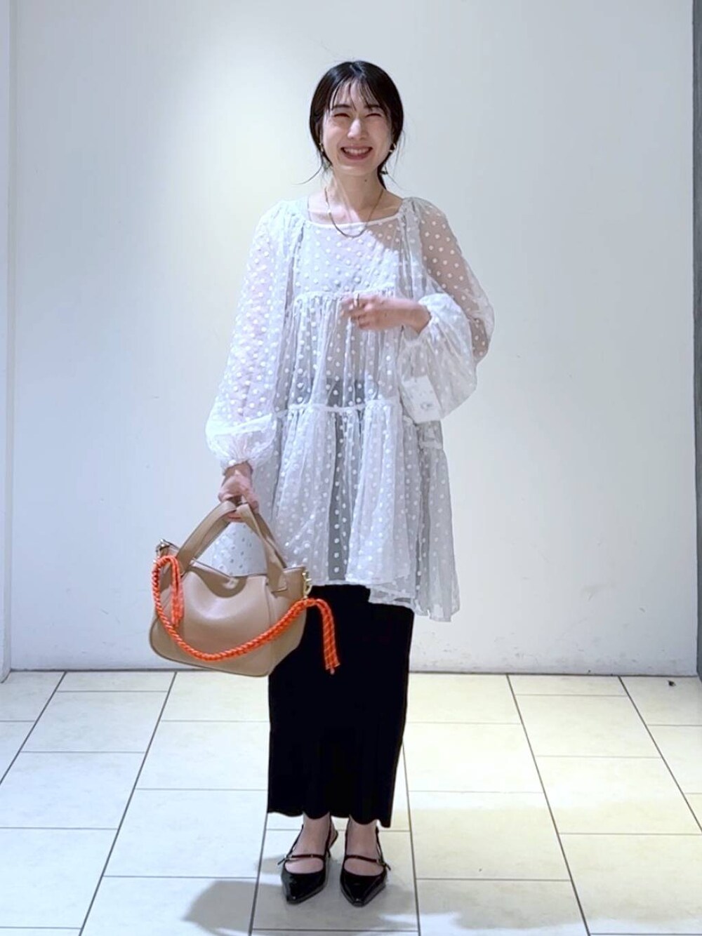 ブラック系のパンプス、ブラック系のスカート、ホワイト系のワンピースを着用したレディースの春コーディネートの1枚目の写真
