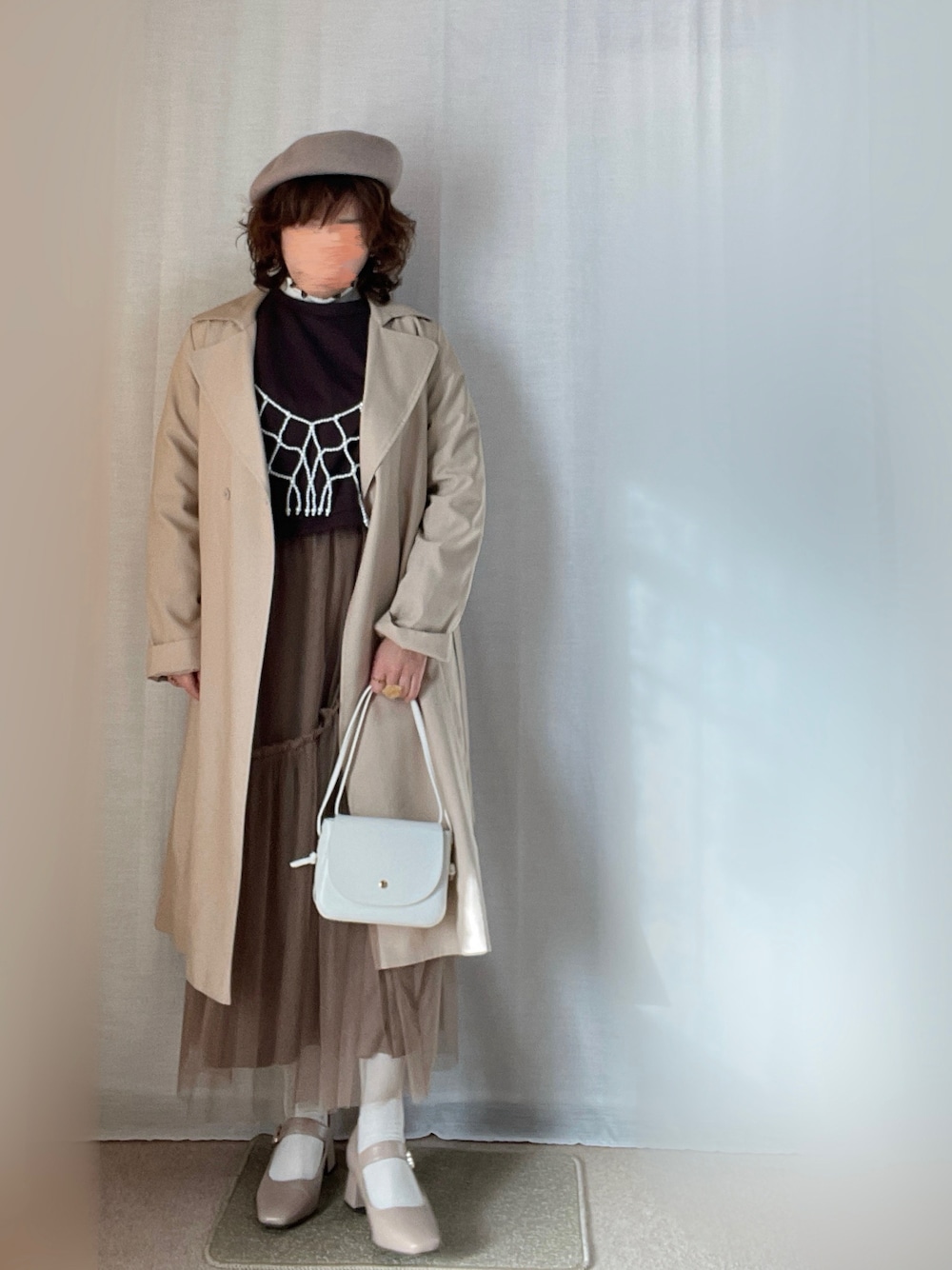 ホワイト系のキャミソール、ベージュ系のトレンチコート、ブラウン系のカーディガン/ボレロを着用したレディースの春コーディネートの1枚目の写真