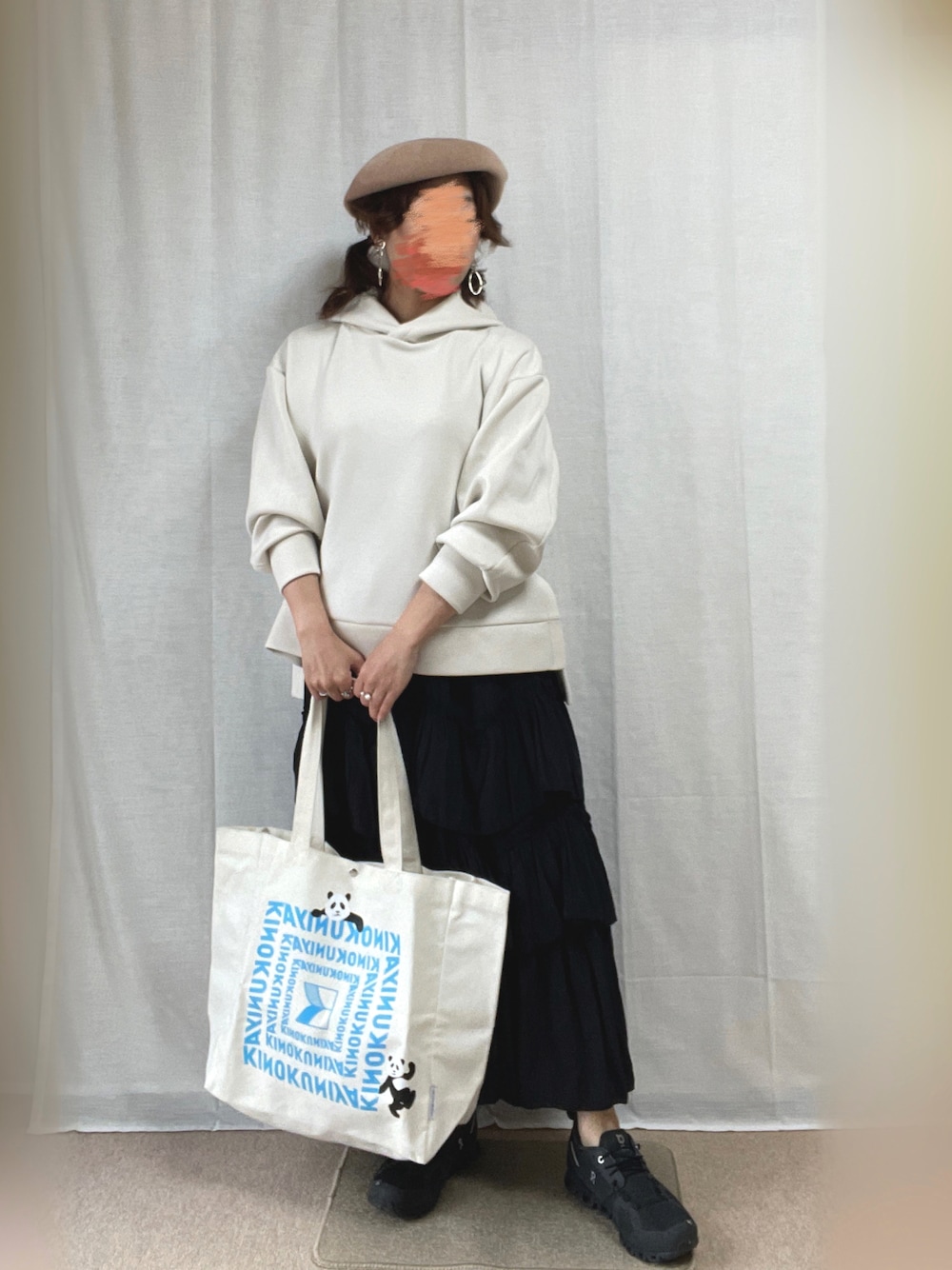 ホワイト系のパーカー、ブラック系のスカート、ブラック系のスニーカーを着用したレディースの春コーディネートの1枚目の写真