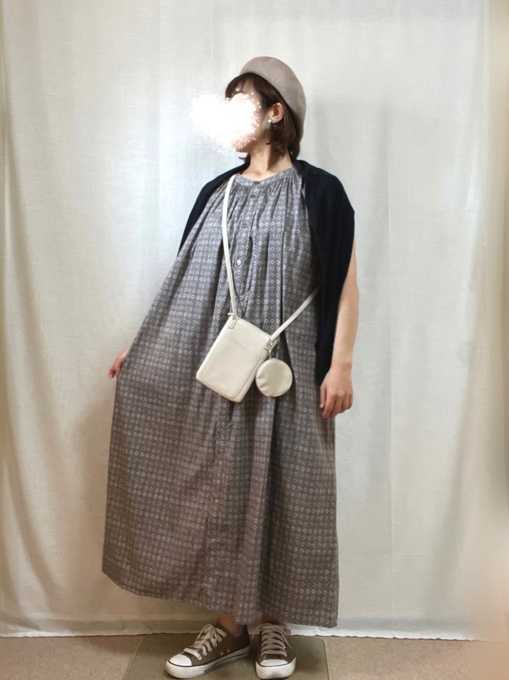 グレー系のワンピース、ホワイト系のショルダーバッグ、ブラウン系のスニーカーを着用したレディースの秋コーディネートの1枚目の写真
