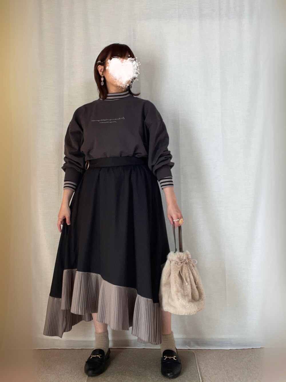 グレー系のスウェット、ベージュ系のショルダーバッグ、ブラック系のスカートを着用したレディースの冬コーディネートの1枚目の写真