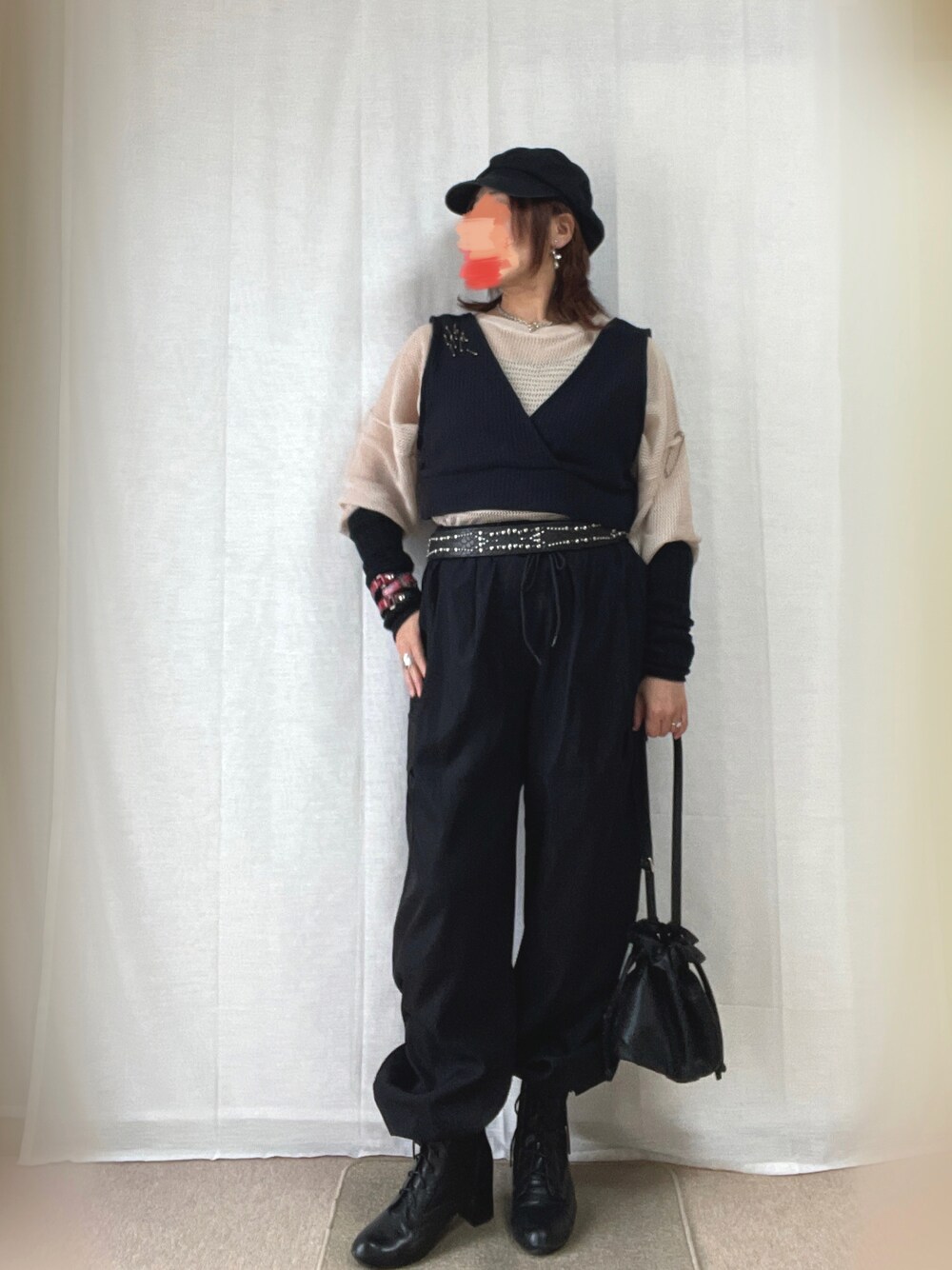 ブラック系のベスト、ベージュ系のニット/セーター、ブラック系のカーゴパンツを着用したレディースの春コーディネートの1枚目の写真