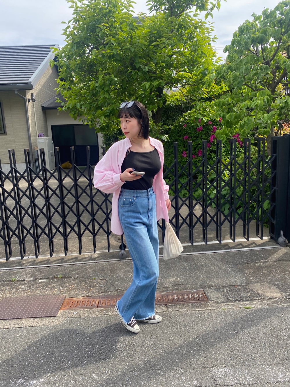 ピンク系のシャツ/ブラウス、ブラック系のキャミソール、ブルー系のデニムパンツを着用したレディースの春コーディネートの1枚目の写真