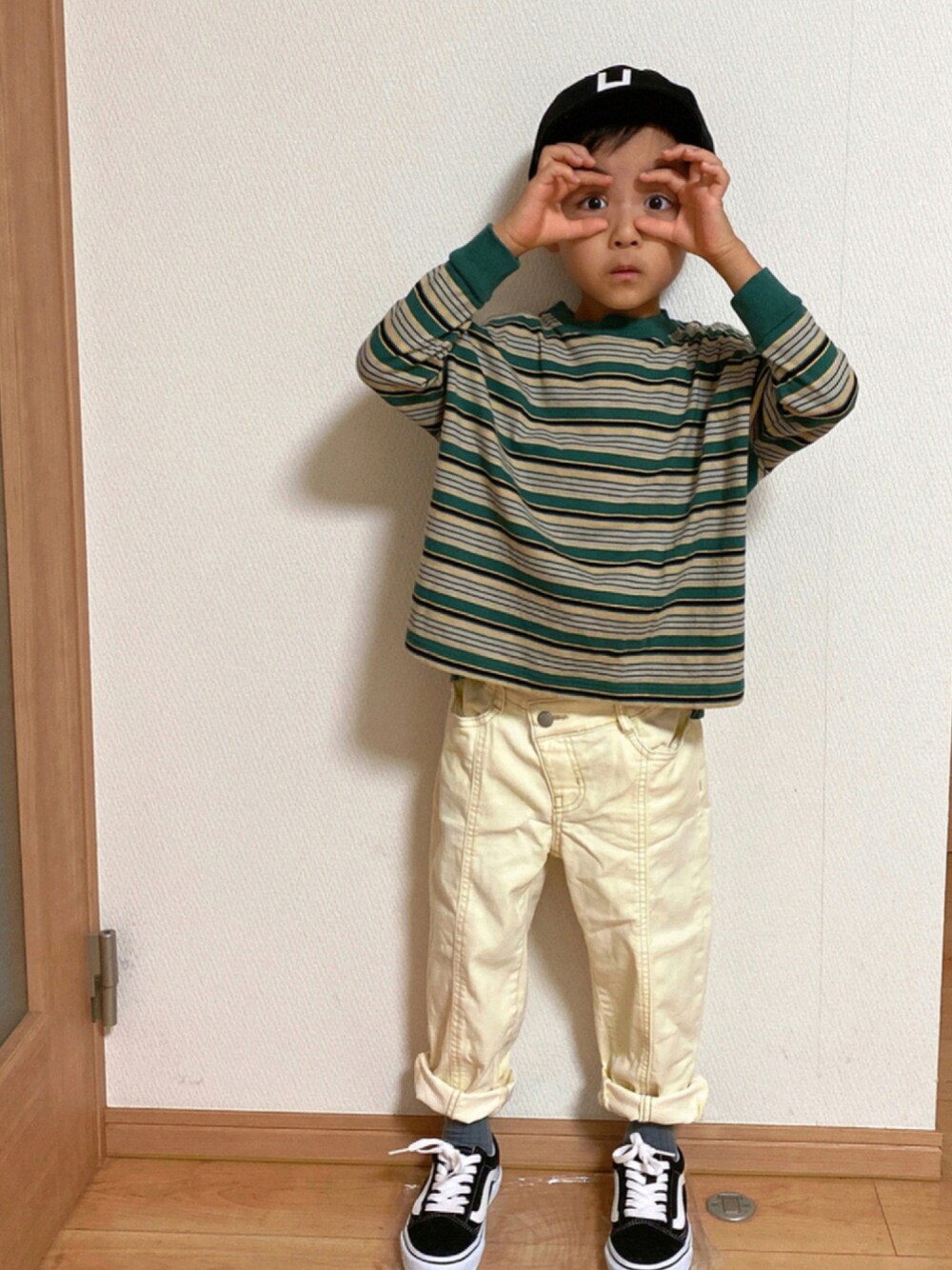 グリーン系のTシャツ/カットソー、ホワイト系のデニムパンツ、ブラック系のスニーカーを着用したキッズの秋コーディネートの1枚目の写真