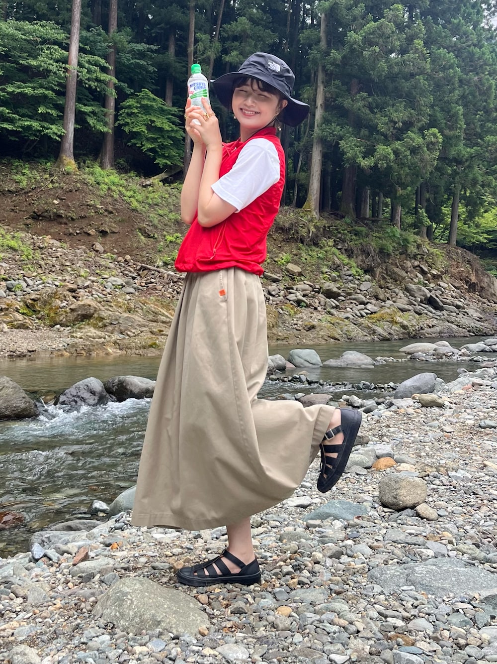 ベージュ系のスカート、レッド系のベスト、ホワイト系のTシャツ/カットソーを着用したレディースの夏コーディネートの1枚目の写真