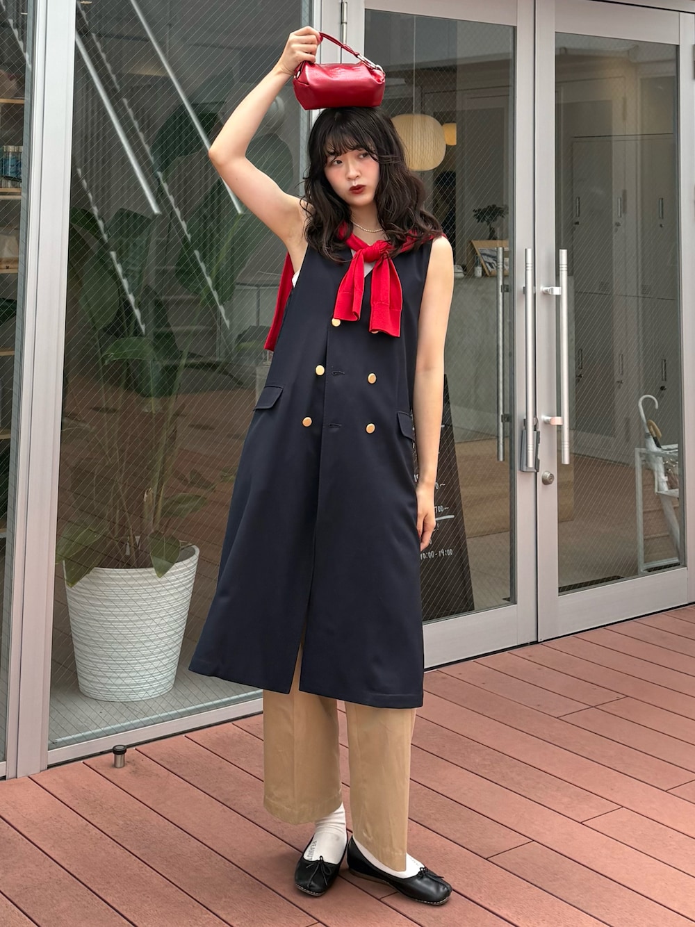 ブラック系のバレエシューズ、レッド系のクラッチバッグ、ベージュ系のチノパンツを着用したレディースの夏コーディネートの1枚目の写真