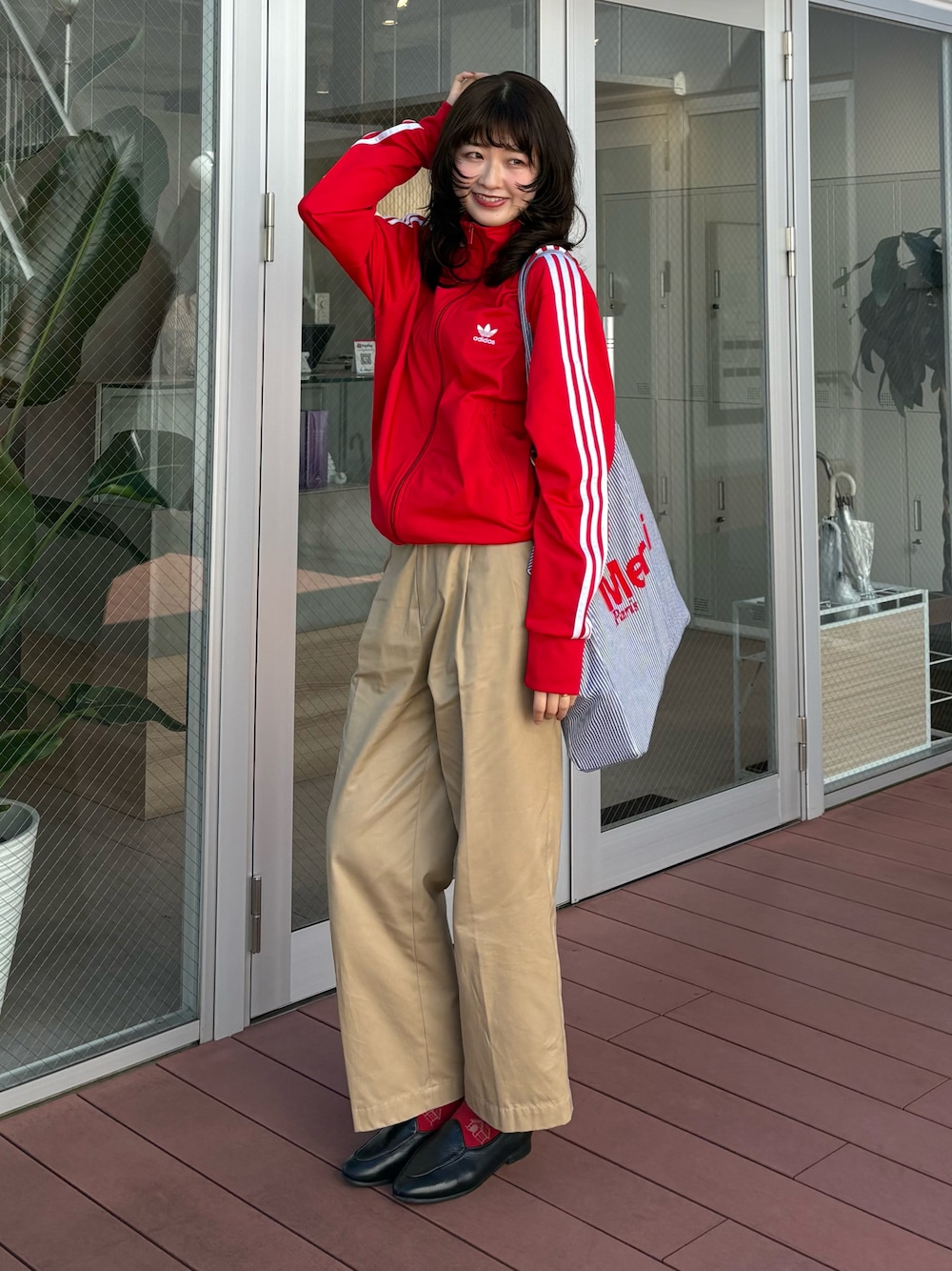 ベージュ系のチノパンツ、ブラック系のローファー、レッド系のジャージを着用したレディースの秋コーディネートの1枚目の写真