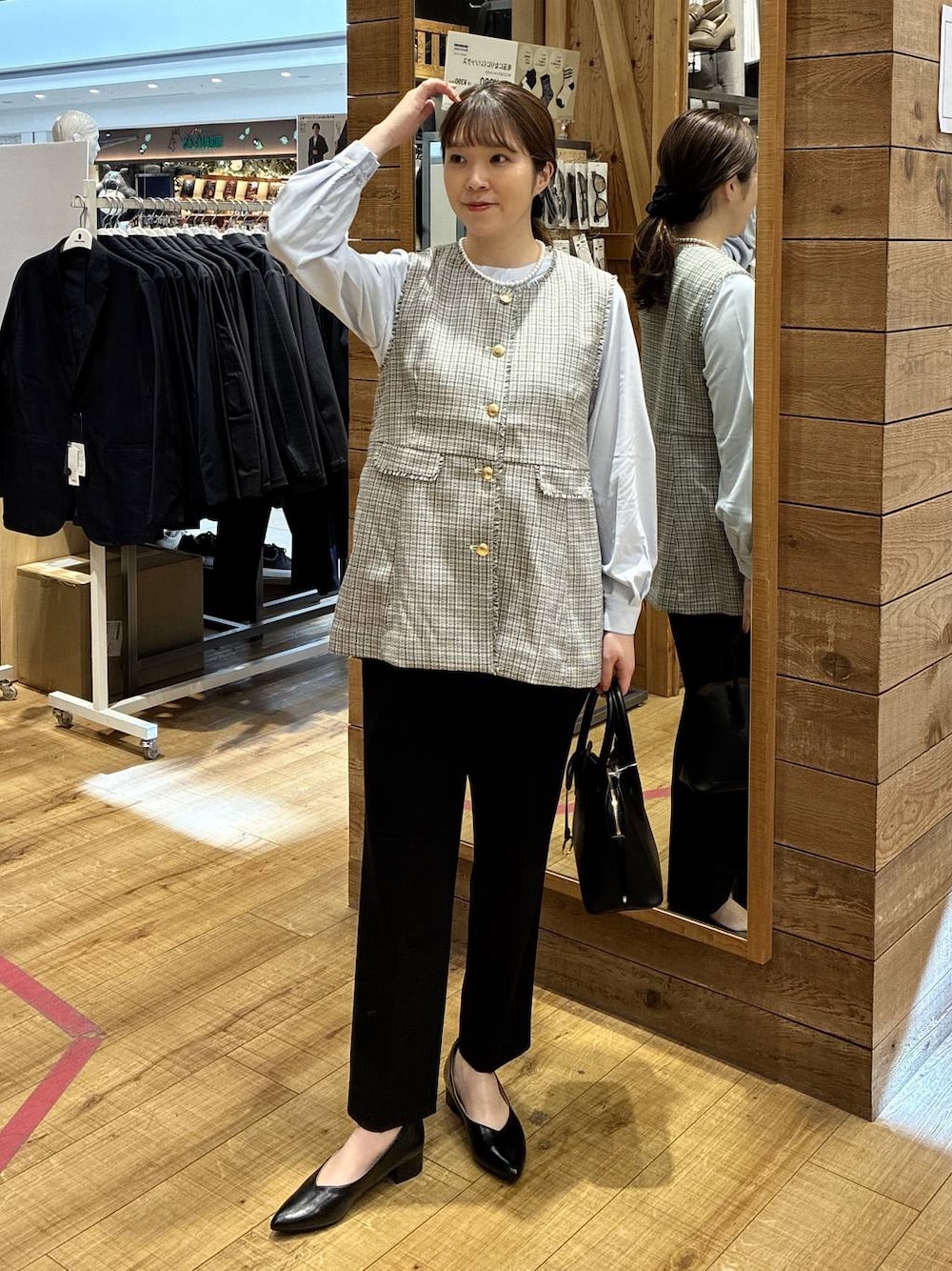 ブラック系のショルダーバッグ、ブラック系のパンプス、ブラック系のスラックスを着用したレディースの春コーディネートの1枚目の写真