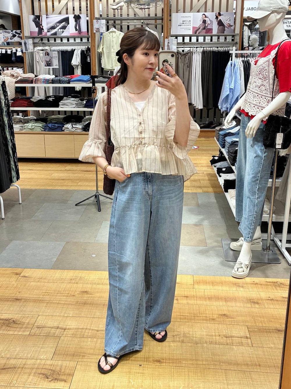 ブルー系のデニムパンツ、ホワイト系のタンクトップ、ブラウン系のトートバッグを着用したレディースの夏コーディネートの1枚目の写真
