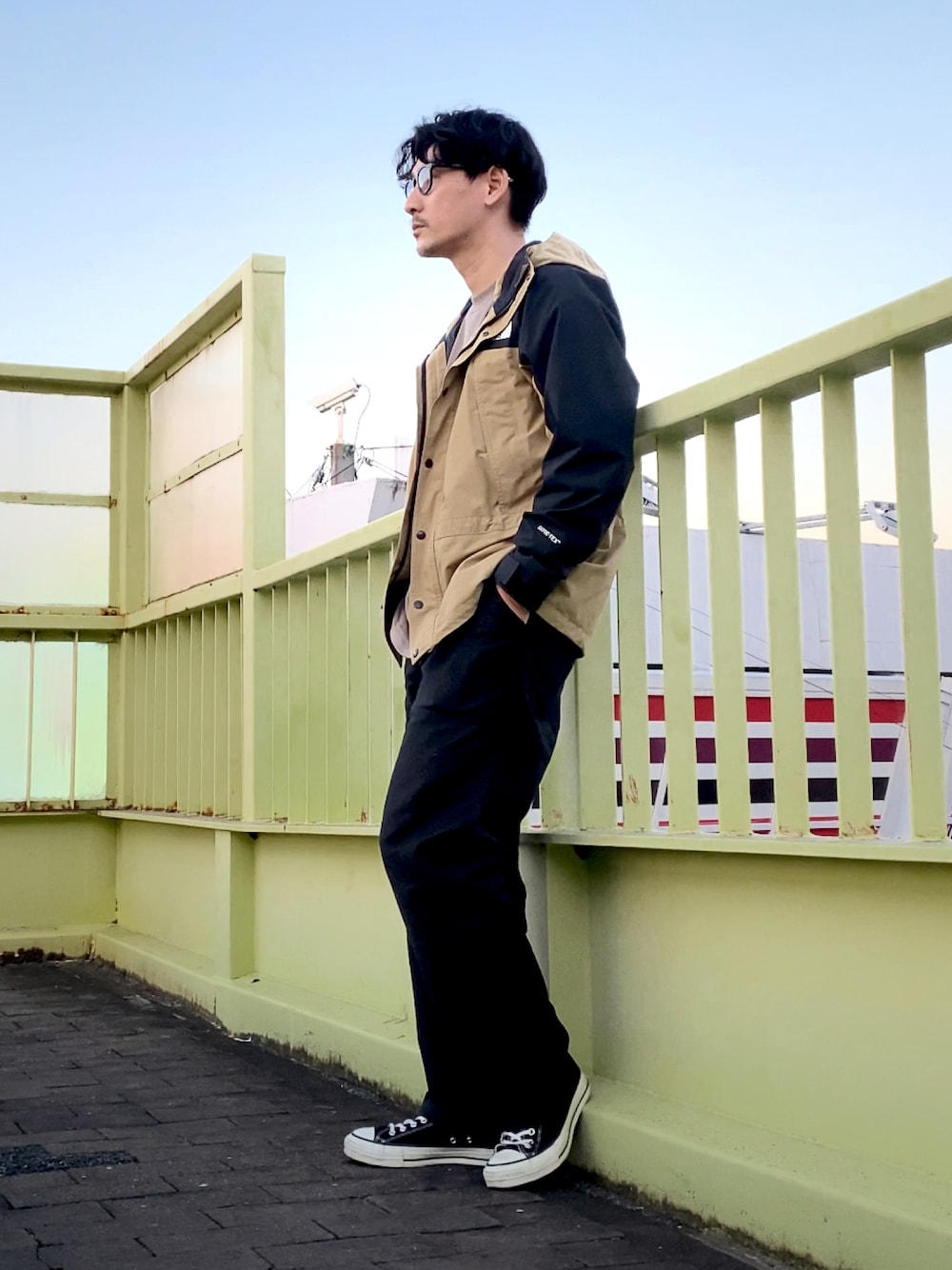 ベージュ系のマウンテンパーカー、ブラック系のチノパンツ、ブラック系のスニーカーを着用したメンズの秋コーディネートの1枚目の写真