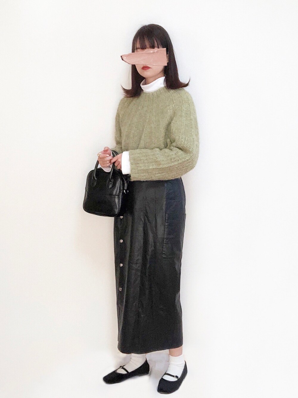 グリーン系のニット/セーター、ホワイト系のTシャツ/カットソー、ブラック系のスカートを着用したレディースの秋コーディネートの1枚目の写真