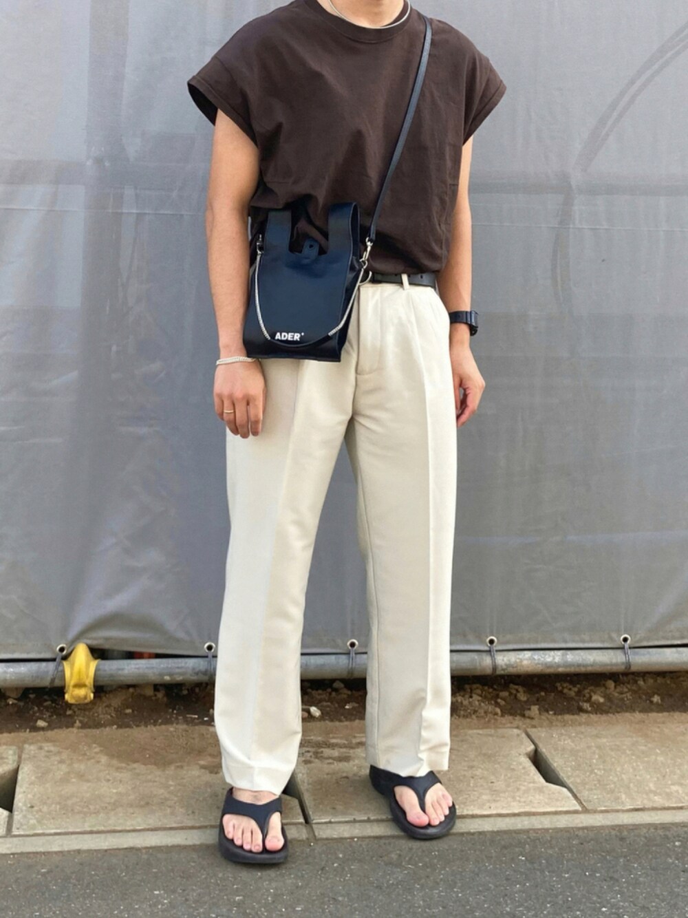 ブラウン系のTシャツ/カットソー、ホワイト系のスラックス、ブラック系のサンダルを着用したメンズの秋コーディネートの1枚目の写真