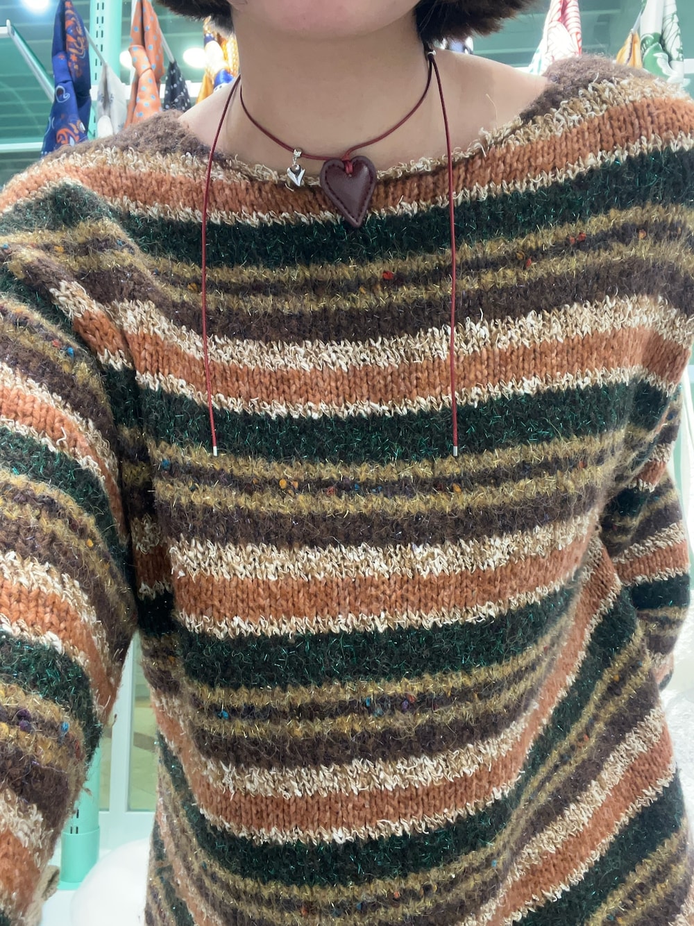 ブラウン系のニット/セーター、レッド系のネックレスを着用したレディースの冬コーディネートの1枚目の写真