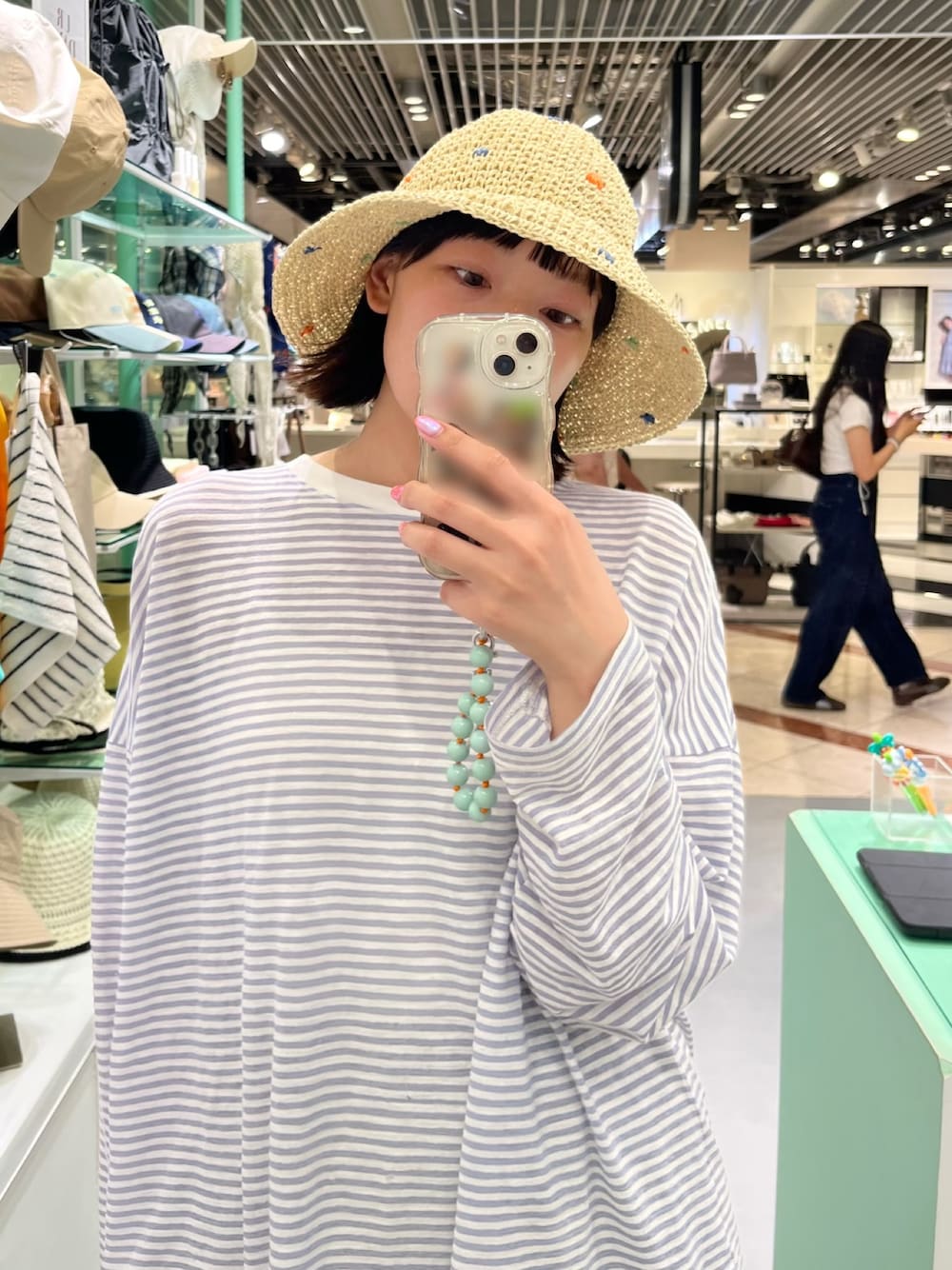 シルバー系のキーホルダー、ホワイト系のハットを着用したレディースの夏コーディネートの1枚目の写真