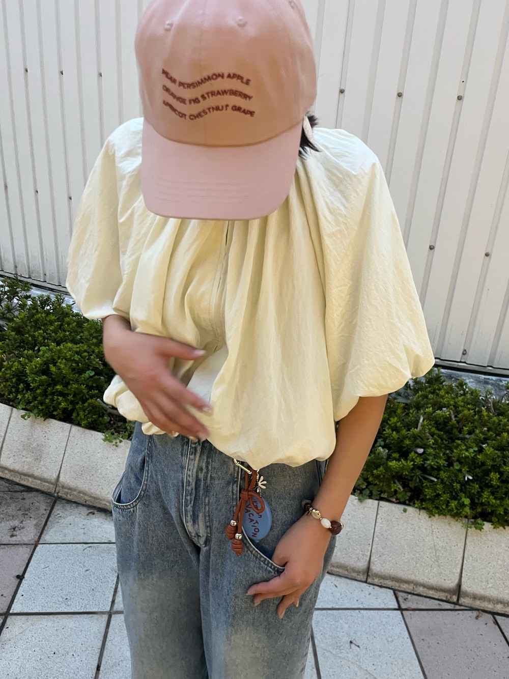 ピンク系のキャップ、ブルー系のキーホルダー、ブラウン系のヘアゴムを着用したレディースの秋コーディネートの1枚目の写真