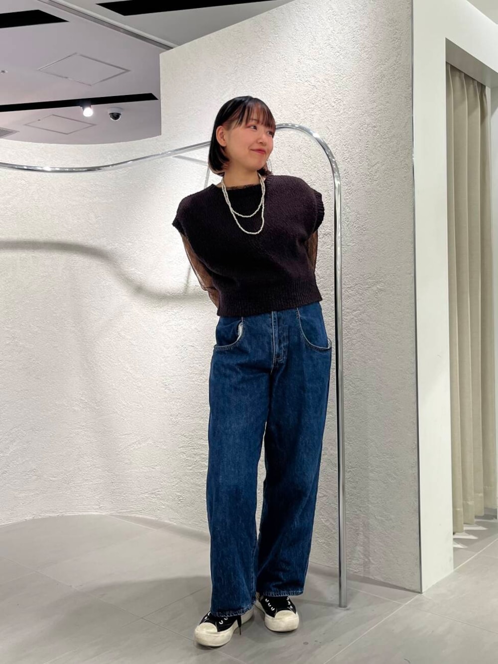 ブルー系のデニムパンツ、ブラック系のTシャツ/カットソー、ブラウン系のニット/セーターを着用したレディースの春コーディネートの1枚目の写真