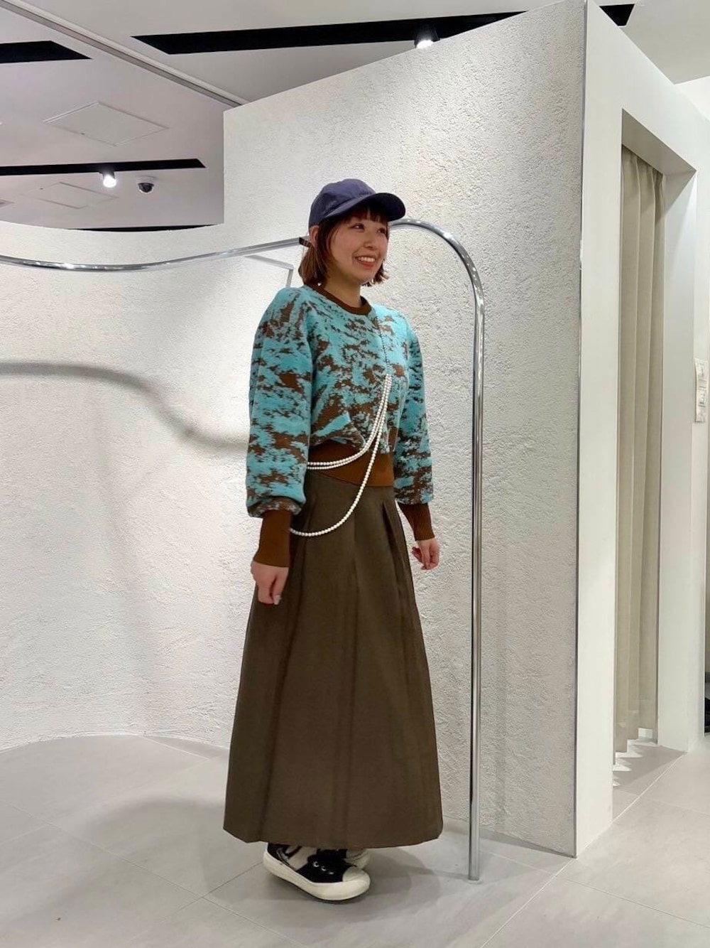 ブラウン系のニット/セーター、ブラウン系のワンピース、ブルー系のキャップを着用したレディースの冬コーディネートの1枚目の写真