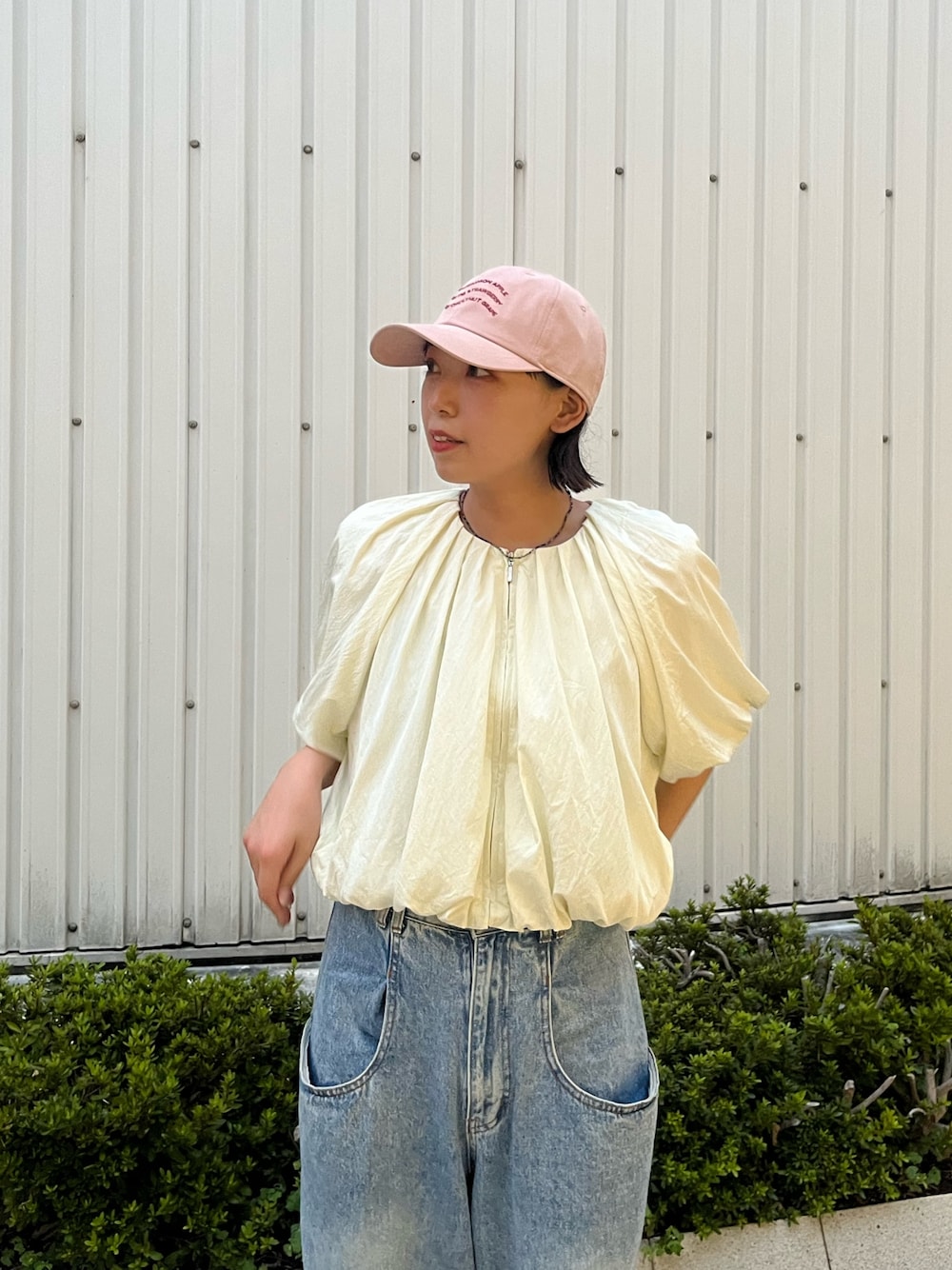 ブルー系のデニムパンツ、ピンク系のキャップ、ブルー系のネックレスを着用したレディースの秋コーディネートの1枚目の写真