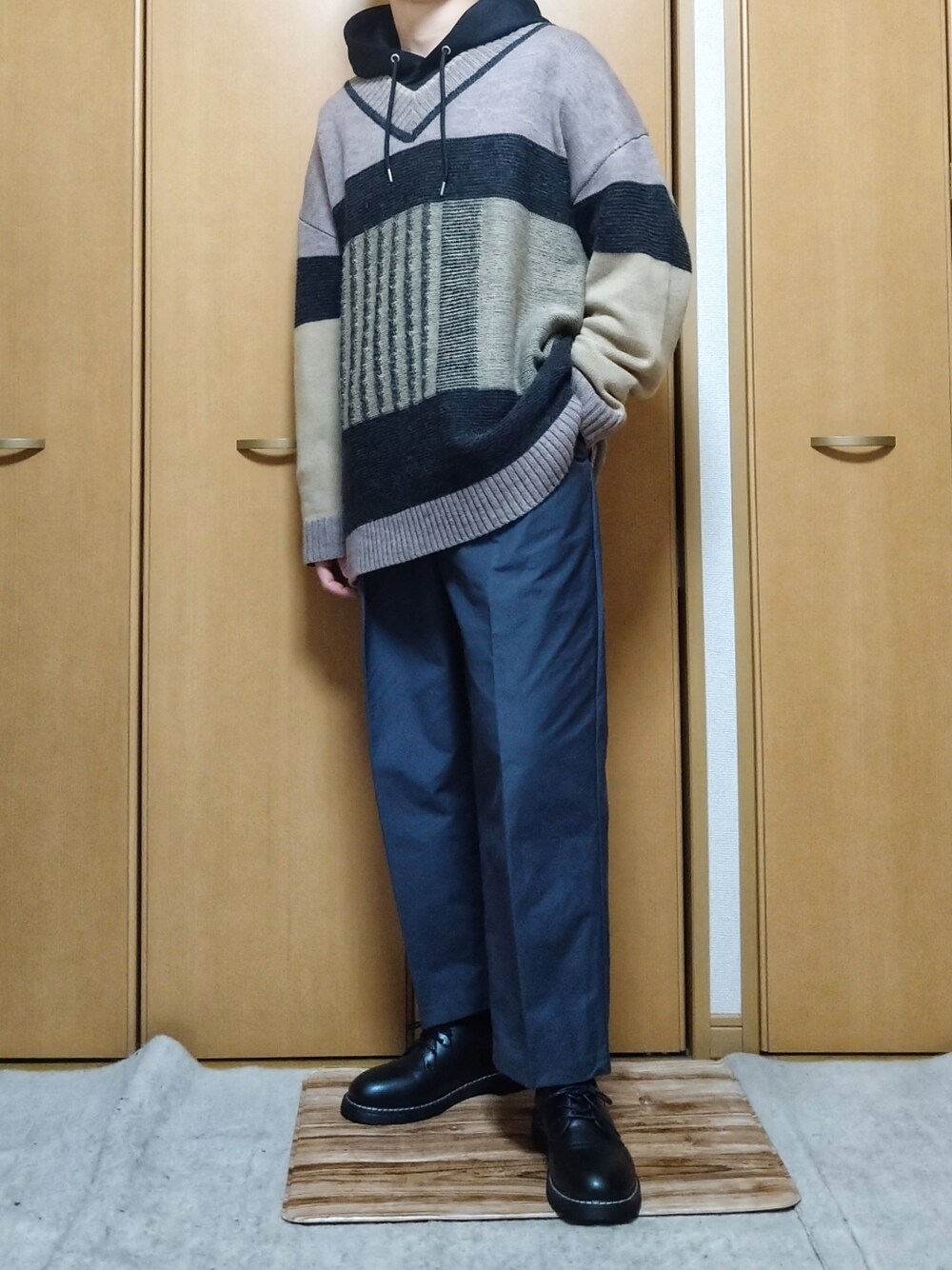 グレー系のパンツ、ベージュ系のニット/セーター、ブラック系のドレスシューズを着用したメンズの春コーディネートの1枚目の写真