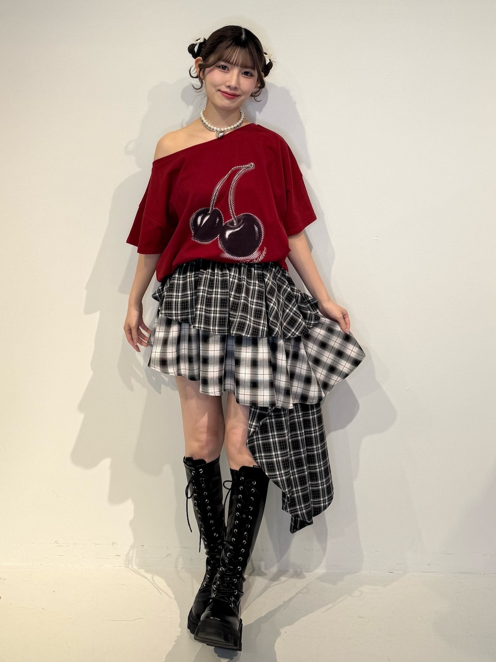 レッド系のTシャツ/カットソー、ブラック系のスカート、ブラック系のブーツを着用したレディースの春コーディネートの1枚目の写真