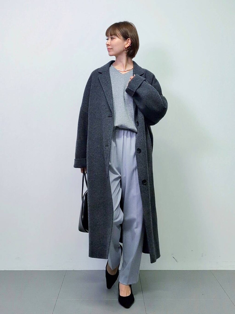 ブラック系のトートバッグ、グレー系のチェスターコート、ブラック系のパンプスを着用したレディースの秋コーディネートの1枚目の写真