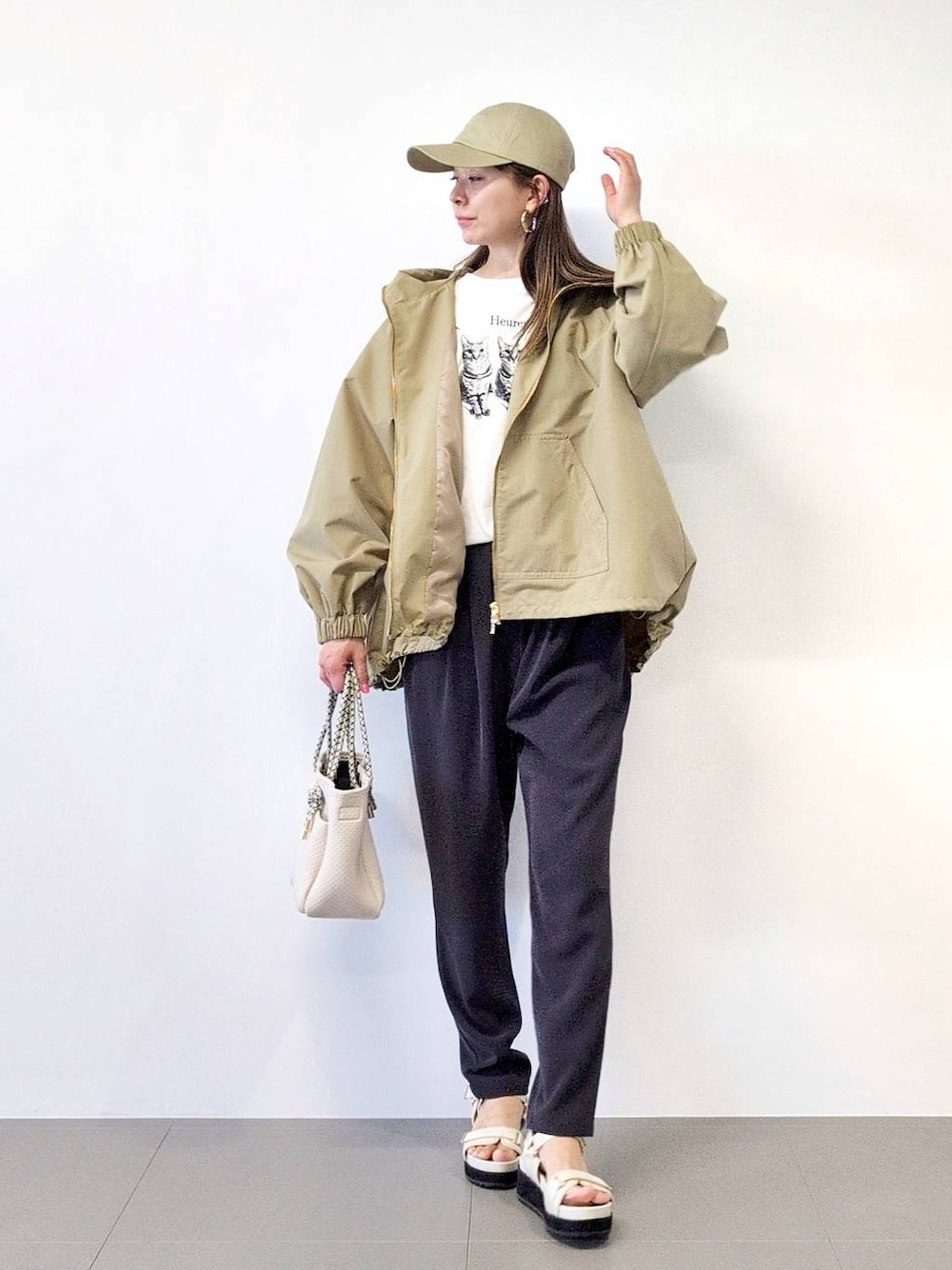 ホワイト系のトートバッグ、ブラック系のスラックス、ベージュ系のブルゾンを着用したレディースの冬コーディネートの1枚目の写真