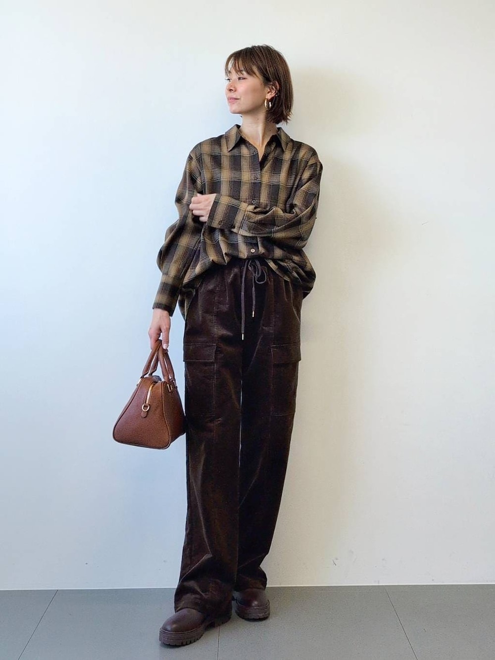 ブラウン系のブーツ、ブラウン系のボストンバッグ、ブラウン系のシャツ/ブラウスを着用したレディースの冬コーディネートの1枚目の写真