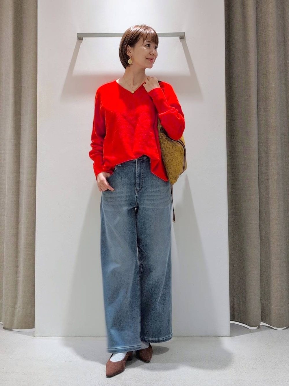 ブルー系のデニムパンツ、ブラウン系のパンプス、イエロー系のショルダーバッグを着用したレディースの秋コーディネートの1枚目の写真