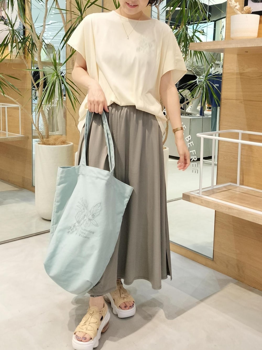 ベージュ系のサンダル、グリーン系のスカート、ベージュ系のTシャツ/カットソーを着用したレディースの夏コーディネートの1枚目の写真