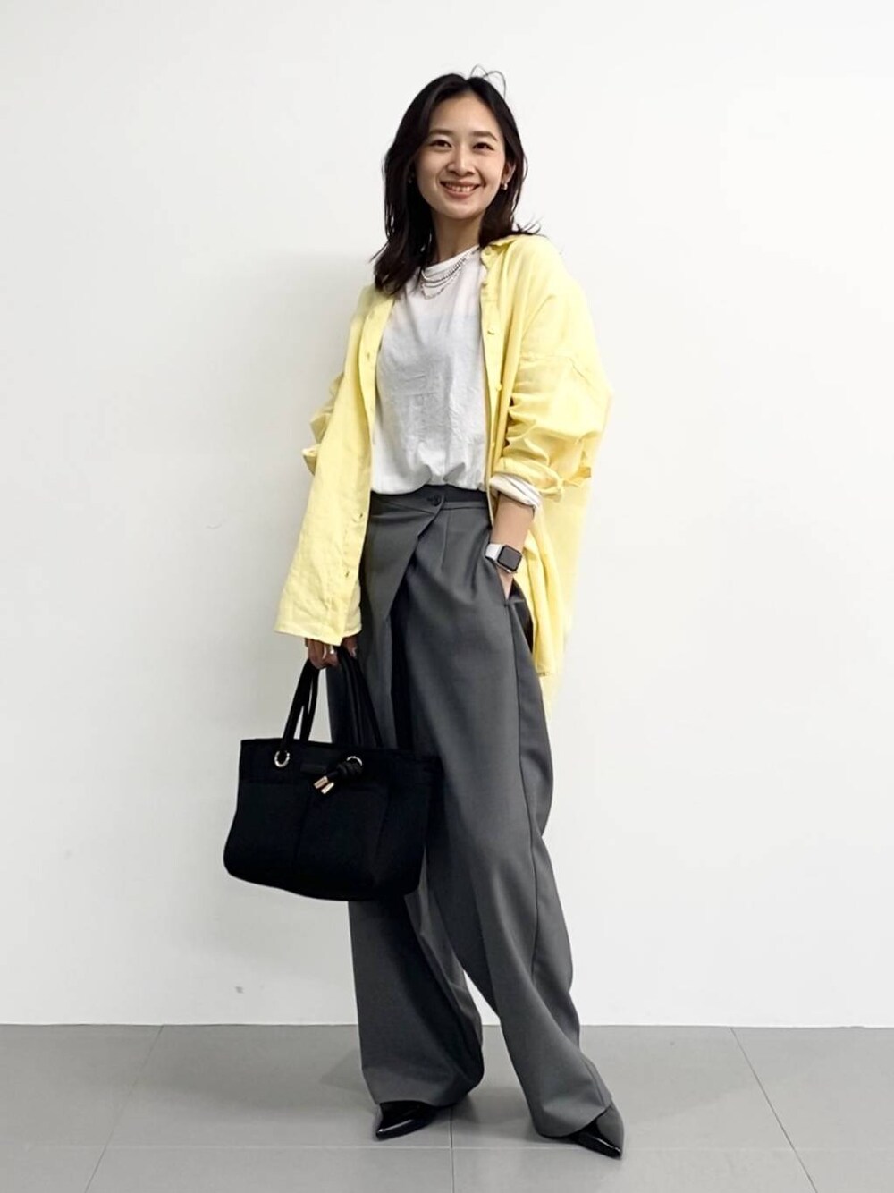 ブラック系のトートバッグ、ホワイト系のTシャツ/カットソー、ブラック系のパンプスを着用したレディースの春コーディネートの1枚目の写真
