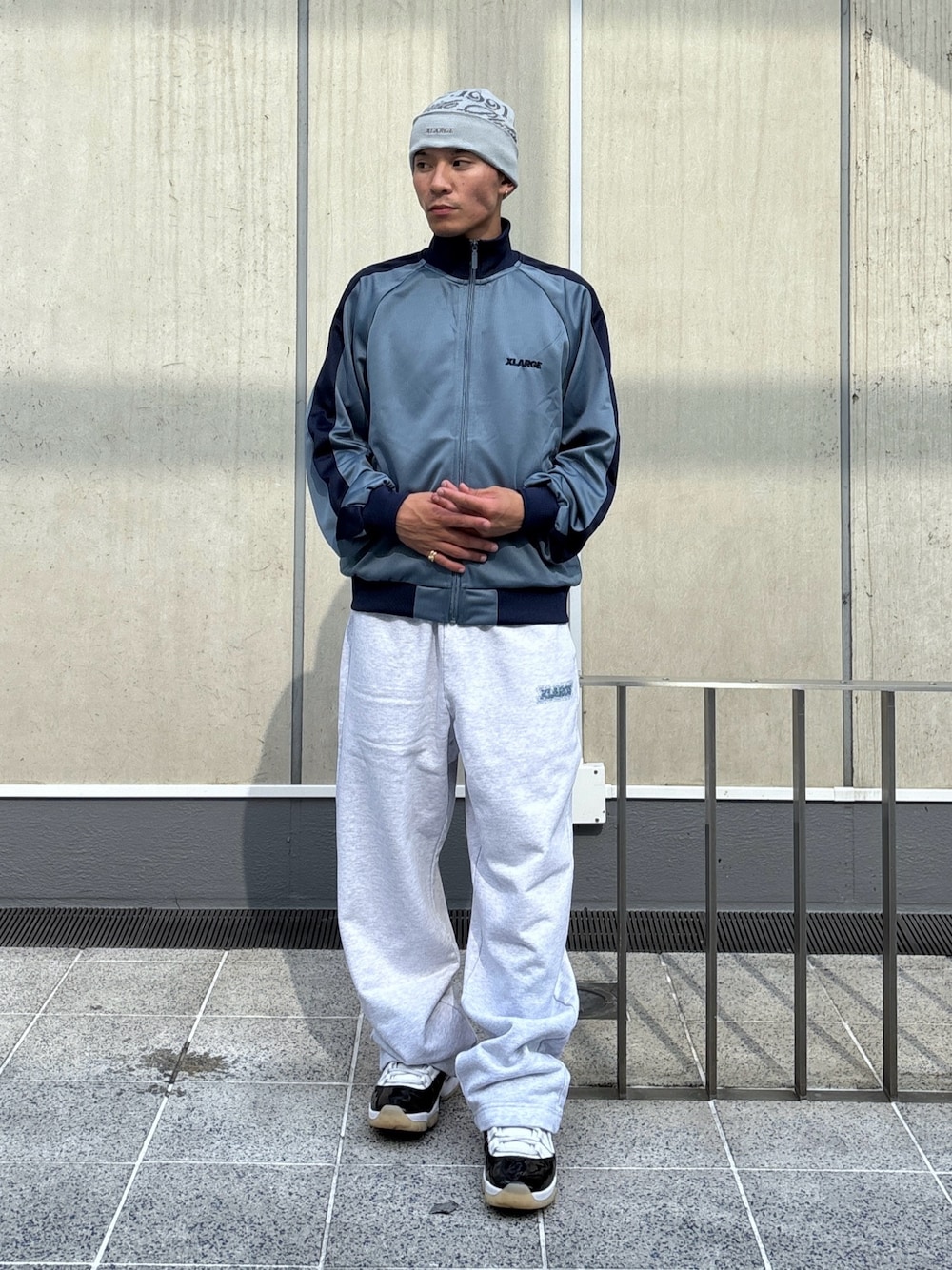 グレー系のスウェットパンツ、ブルー系のブルゾン、ブラック系のニットキャップ/ビーニーを着用したメンズの秋コーディネートの1枚目の写真