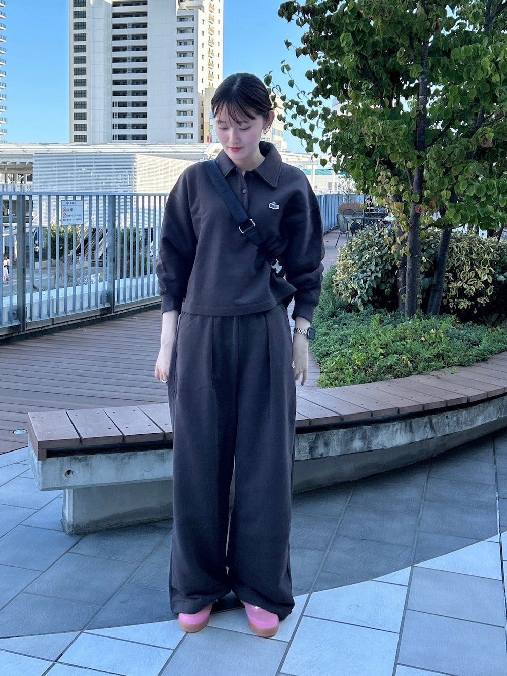 ブラック系のショルダーバッグ、ピンク系のスニーカー、ブラウン系のスウェットを着用したレディースの秋コーディネートの1枚目の写真