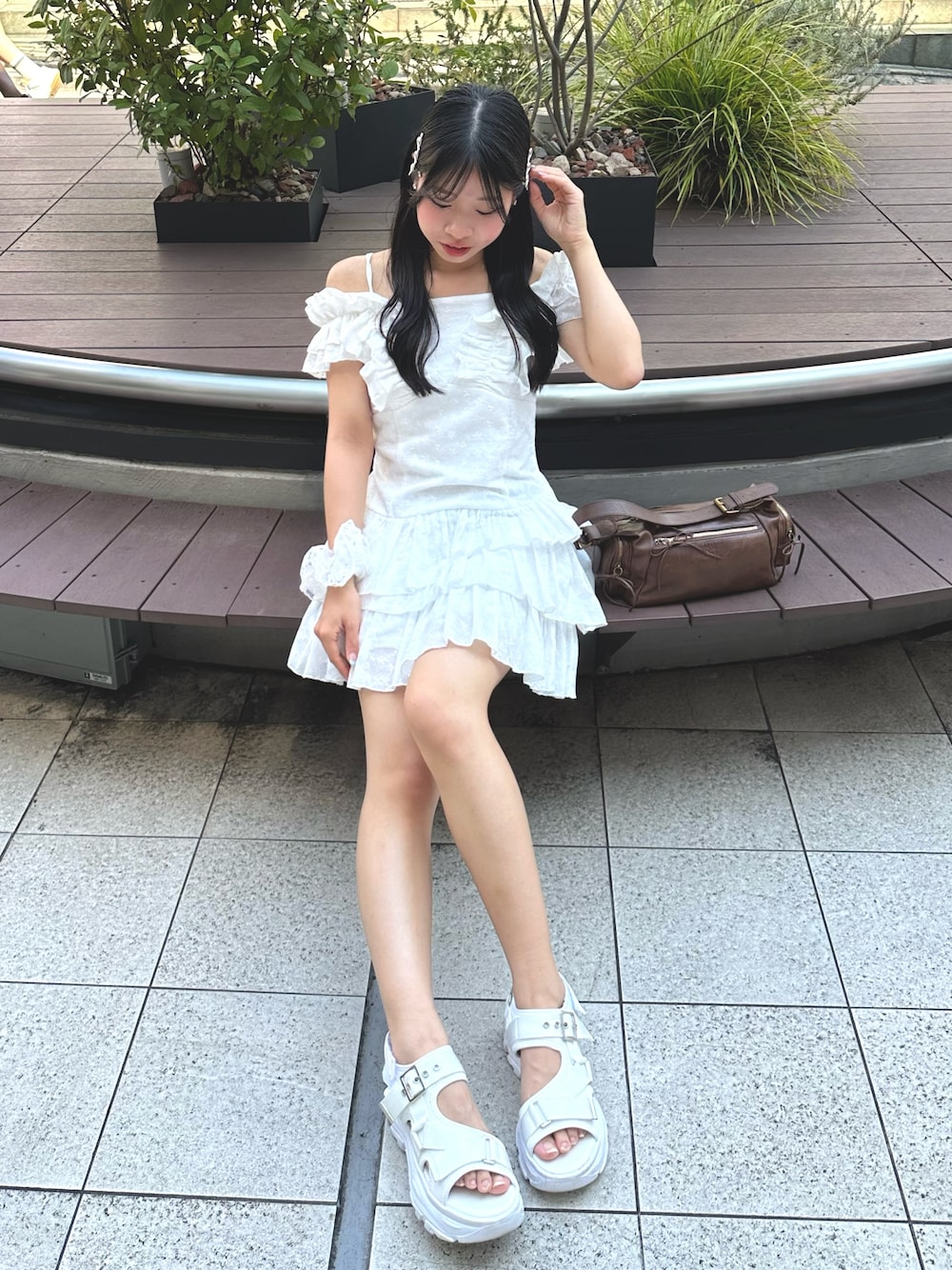 ホワイト系のワンピース、ホワイト系のサンダル、ブラウン系のショルダーバッグを着用したレディースの夏コーディネートの1枚目の写真
