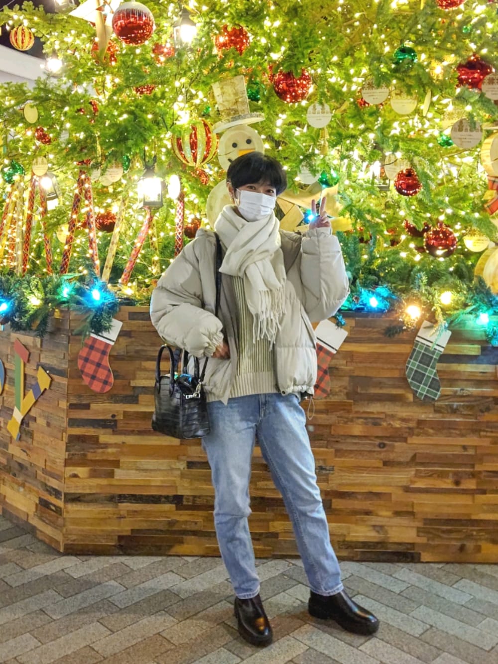 ベージュ系のダウンジャケット/コート、ブラック系のボストンバッグ、ブルー系のデニムパンツを着用したレディースの冬コーディネートの1枚目の写真