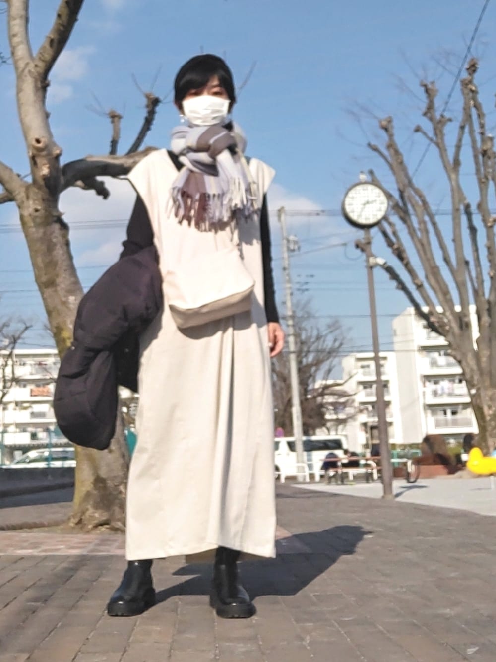 ホワイト系のショルダーバッグ、ホワイト系のジャンパースカート、ブラック系のダウンジャケット/コートを着用したレディースの冬コーディネートの1枚目の写真