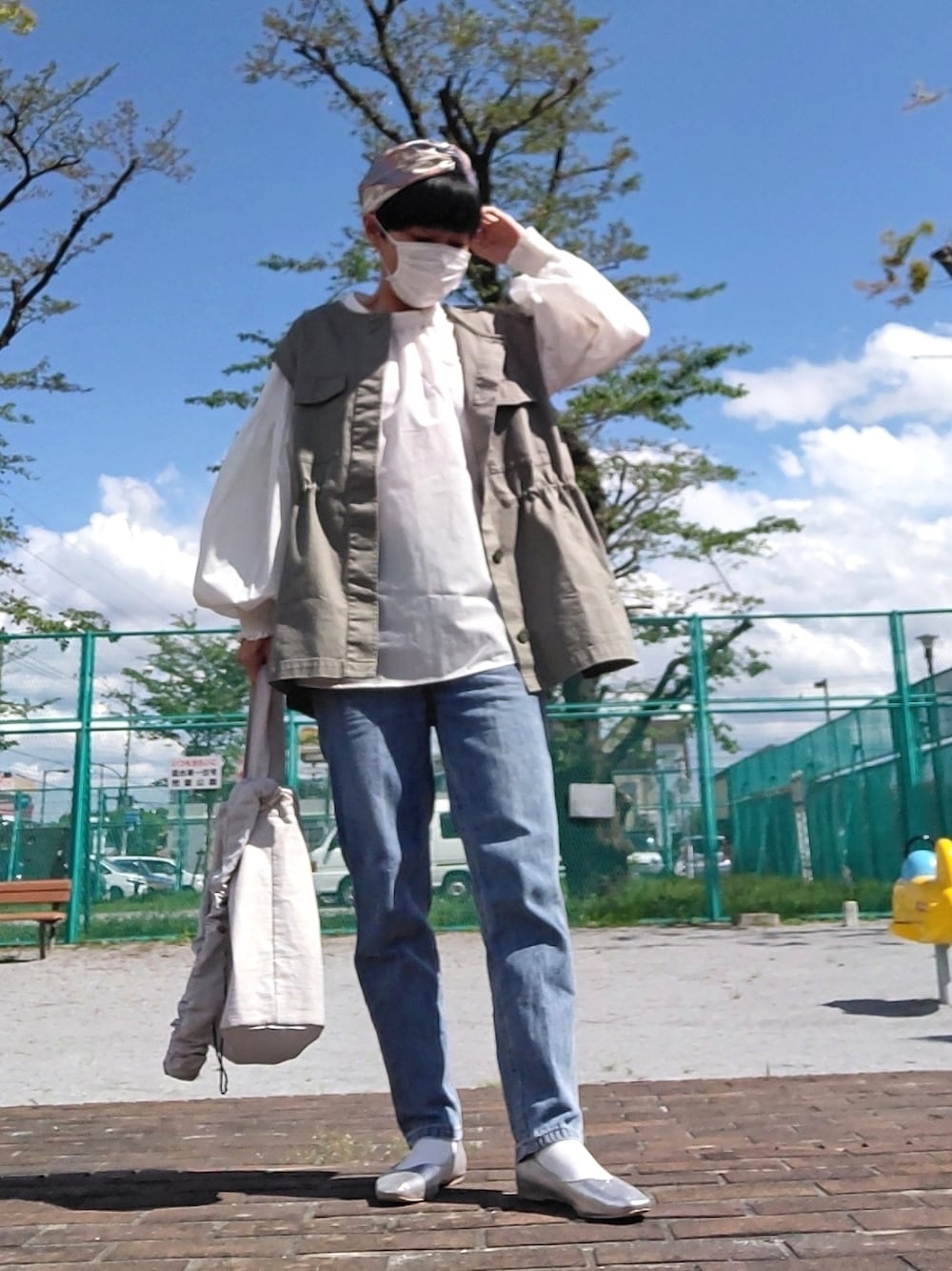 グリーン系のベスト、ホワイト系のシャツ/ブラウス、ブルー系のデニムパンツを着用したレディースの春コーディネートの1枚目の写真