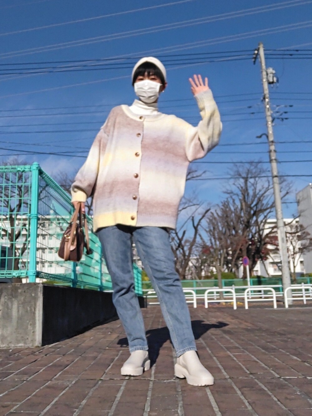 イエロー系のニット/セーター、ブルー系のデニムパンツ、ホワイト系のブーツを着用したレディースの冬コーディネートの1枚目の写真