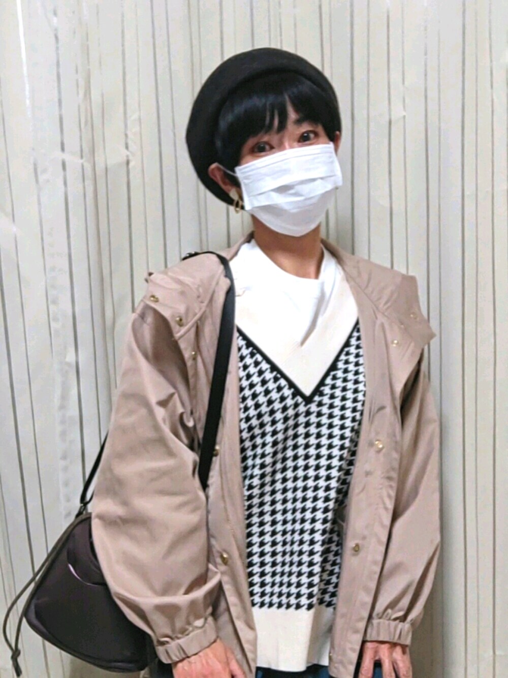 ベージュ系のマウンテンパーカー、ブラック系のベスト、ブラウン系のショルダーバッグを着用したレディースの秋コーディネートの1枚目の写真