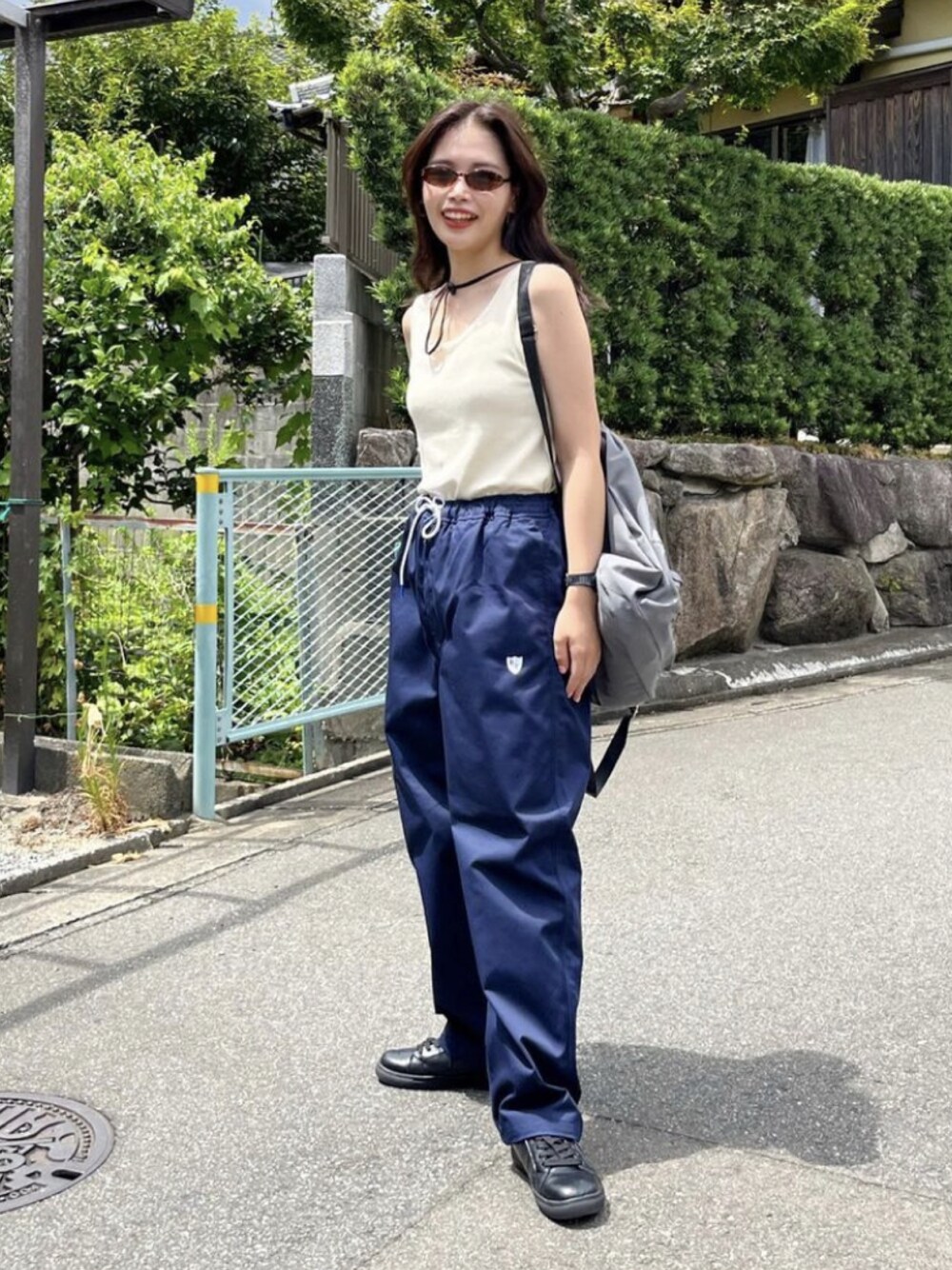 ブルー系のチノパンツ、ホワイト系のタンクトップを着用したレディースの夏コーディネートの1枚目の写真