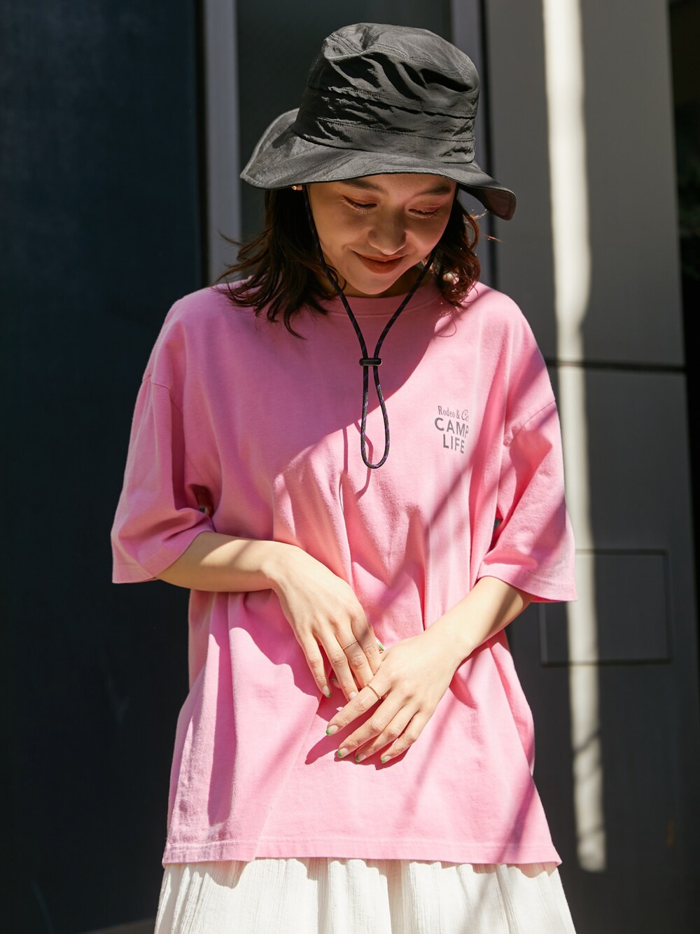 ピンク系のTシャツ/カットソー、ホワイト系のスカート、ブラック系のハットを着用したレディースの春コーディネートの1枚目の写真