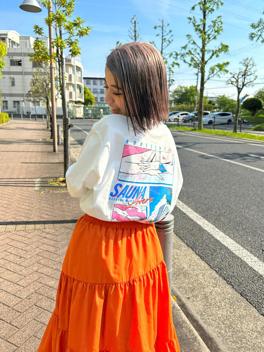 ホワイト系のTシャツ/カットソー、オレンジ系のスカートを着用したレディースの春コーディネートの1枚目の写真