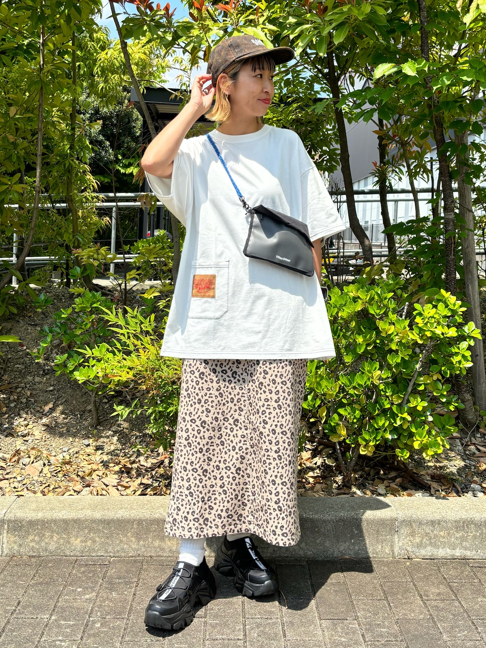 ホワイト系のTシャツ/カットソー、ベージュ系のスカート、ブラック系のショルダーバッグを着用したレディースの春コーディネートの1枚目の写真