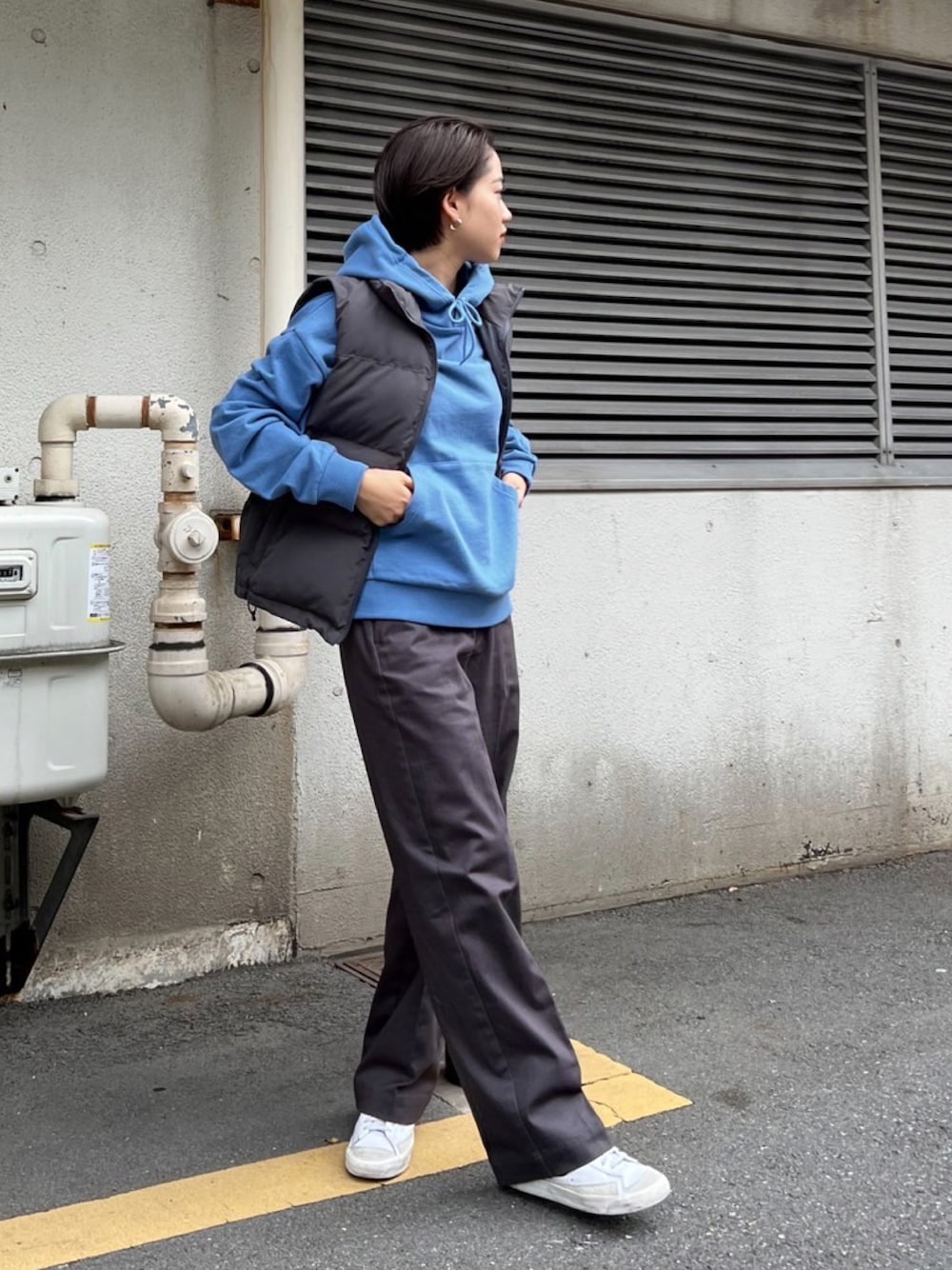 グレー系のベスト、グレー系のその他パンツ、ブルー系のパーカーを着用したレディースの秋コーディネートの1枚目の写真