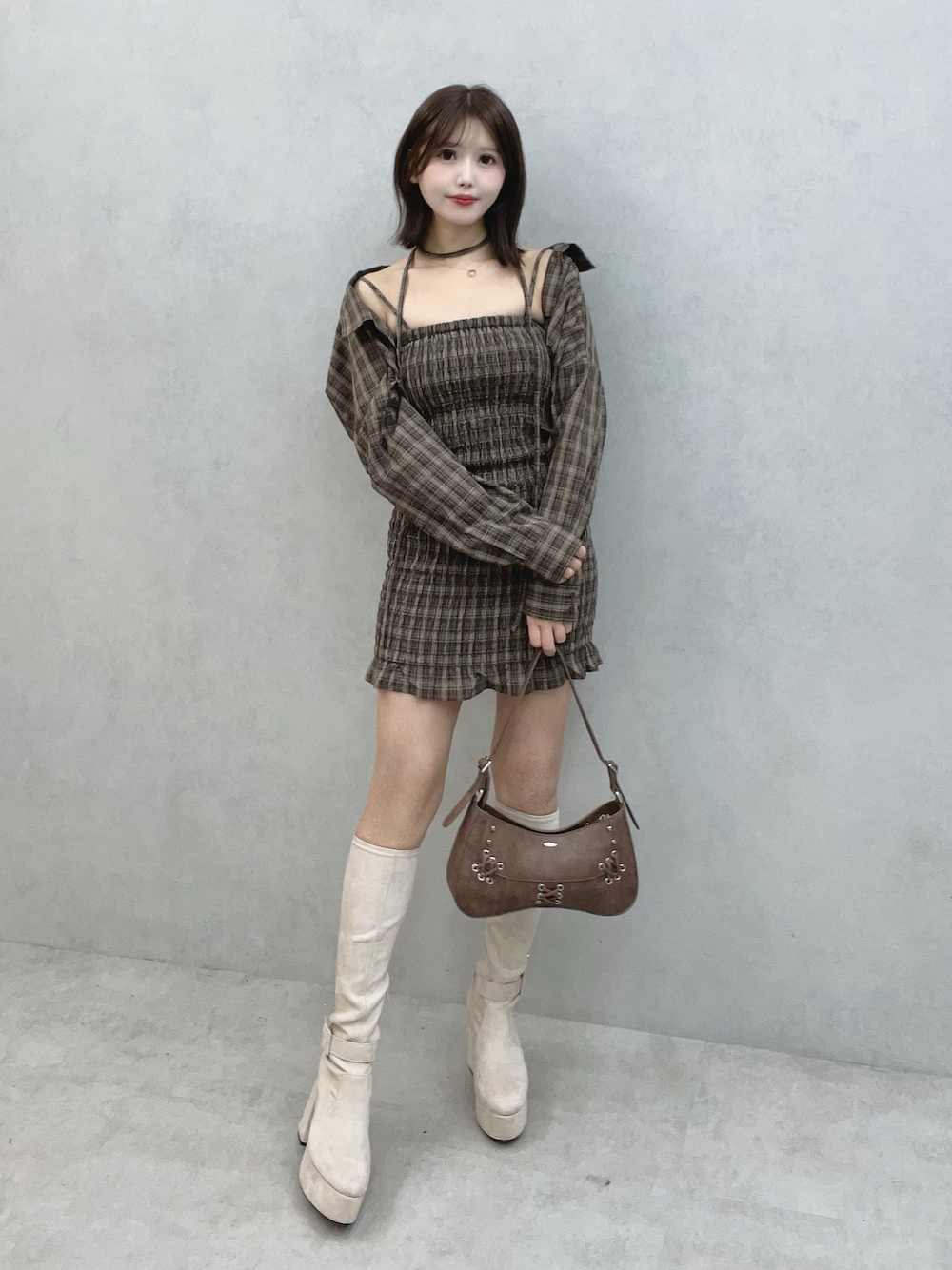 ブラウン系のワンピース、ブラウン系のショルダーバッグ、ホワイト系のブーツを着用したレディースの秋コーディネートの1枚目の写真