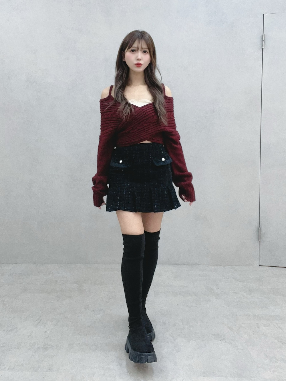 ブラック系のブーツ、ブラック系のスカート、レッド系のニット/セーターを着用したレディースの冬コーディネートの1枚目の写真